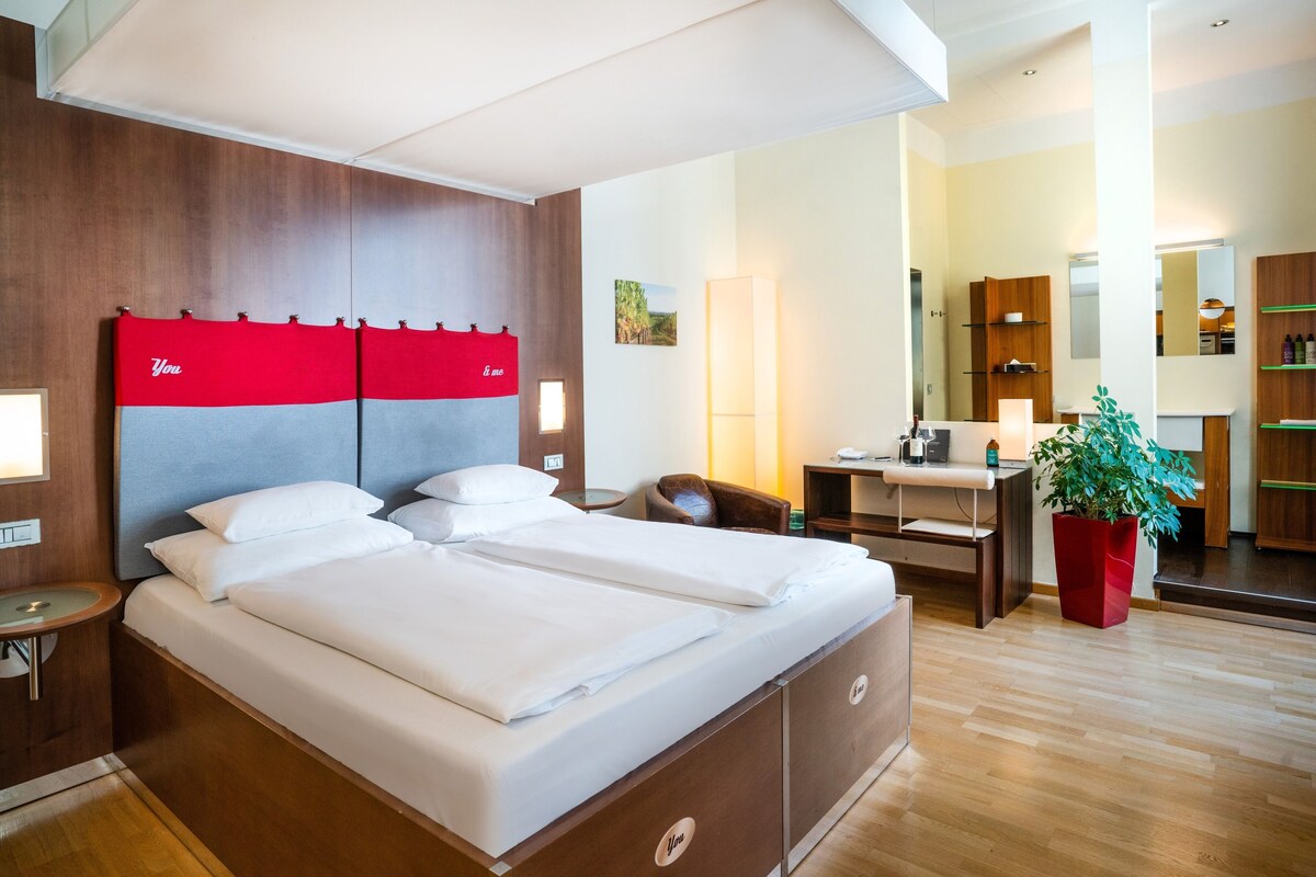 Una habitación de hotel moderna con una cama grande, un escritorio y un espejo.