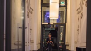 A hallway with a checkered floor, a person walking, and a door labeled "EXIT". - Hotel Rathaus Wein & Design (Vienna)