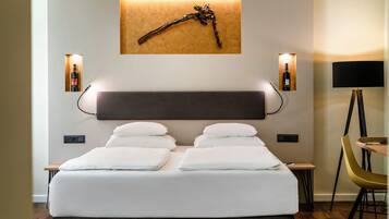 A modern hotel room with a large bed, bedside tables, a desk, and a chair.