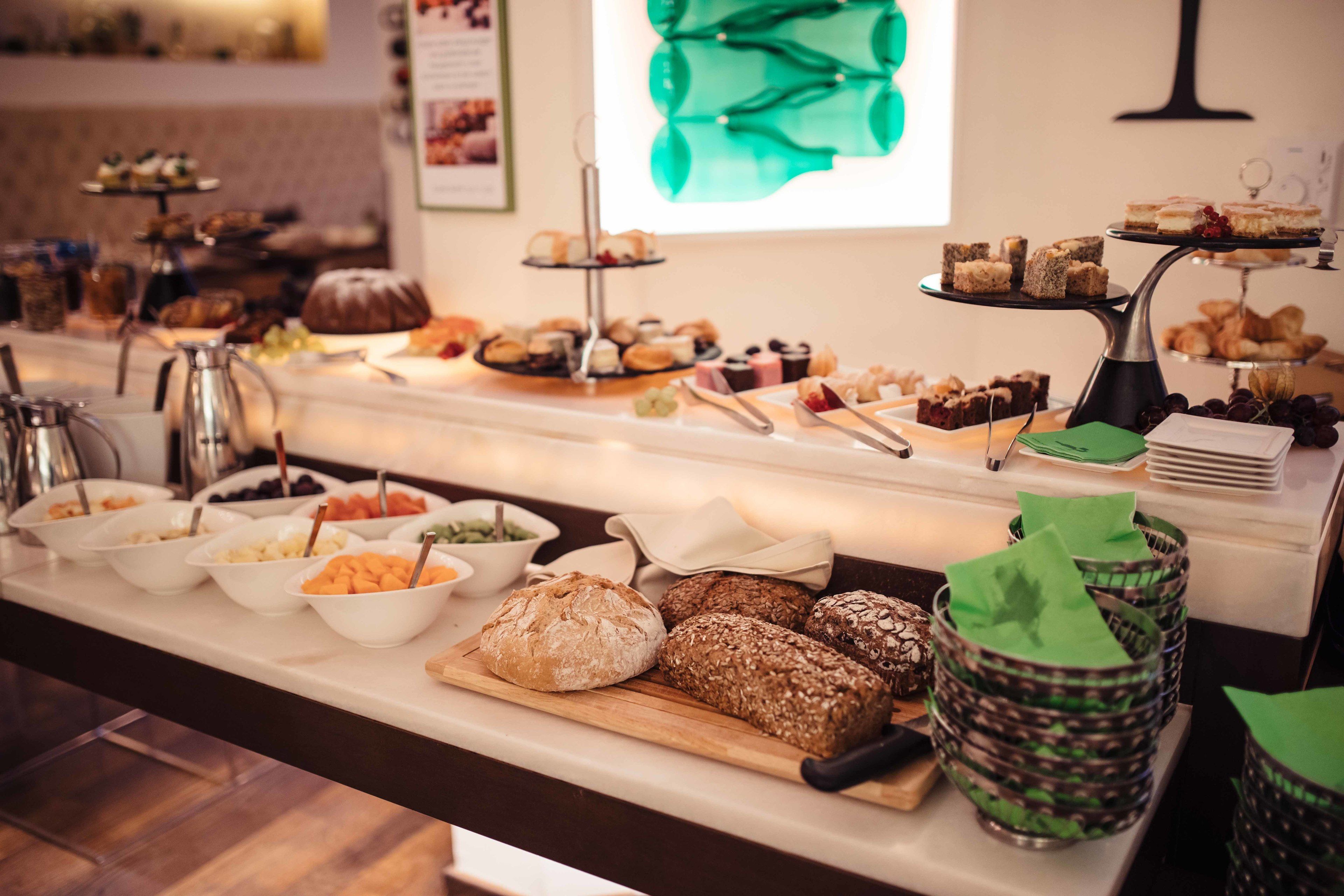 Un bufé con panes, pasteles y postres variados.