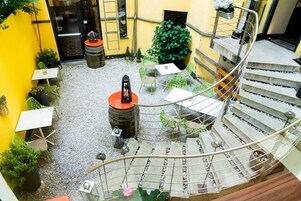 Ein Innenhof mit Sitzgelegenheiten im Freien, einer Wendeltreppe und Topfpflanzen.