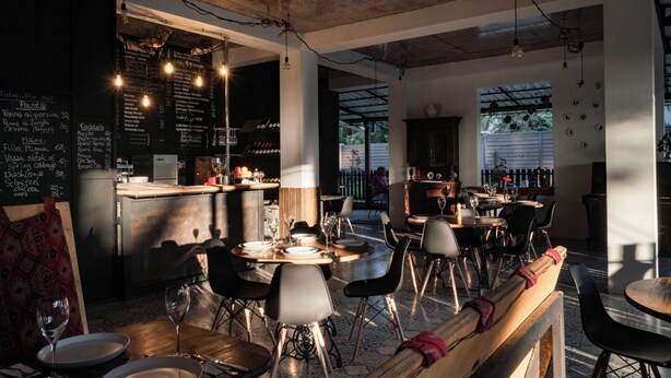 Ein Restaurant mit einer Kreidetafel, Tischen mit Stühlen und einer Bar.