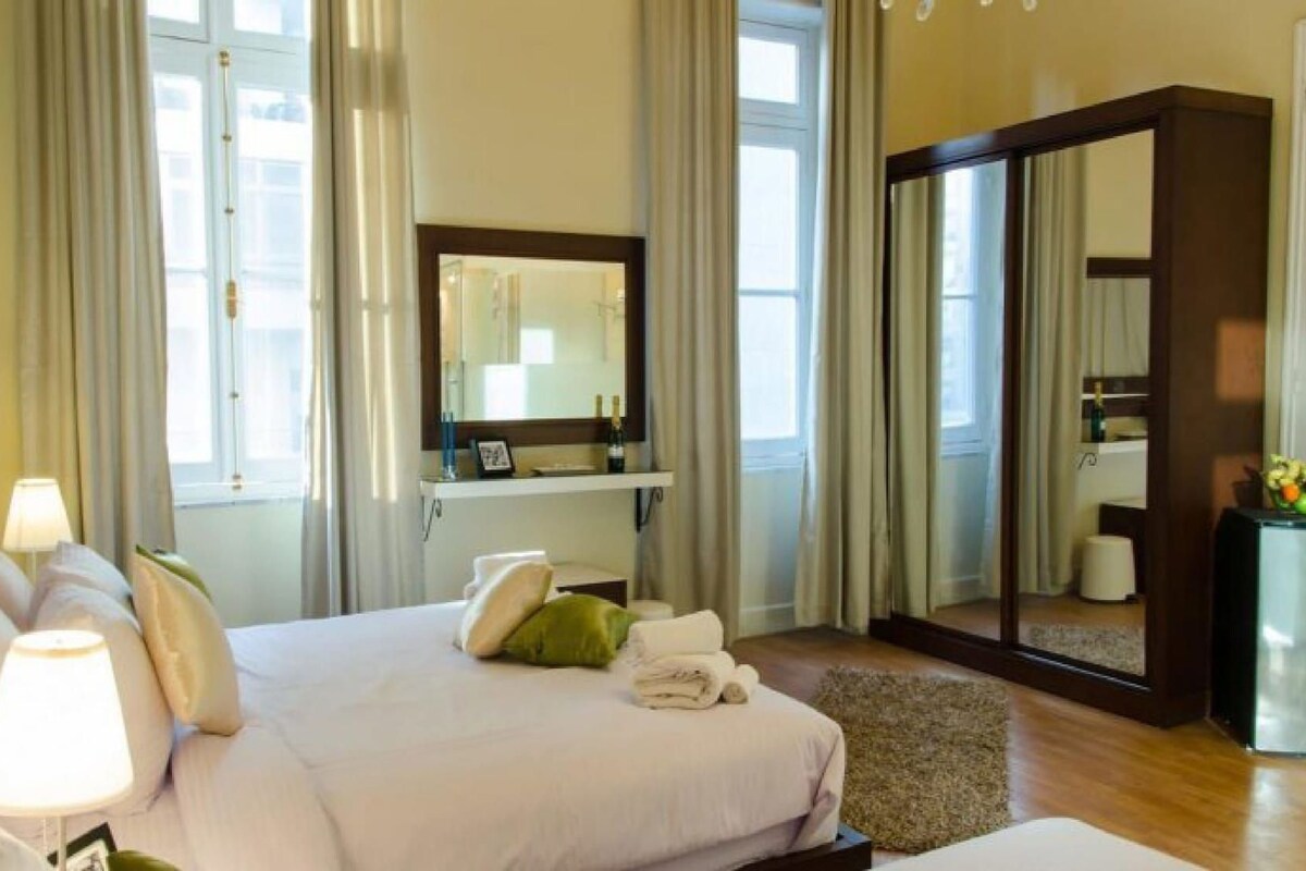 A hotel room with a bed, a mirror, a desk, and a wardrobe.