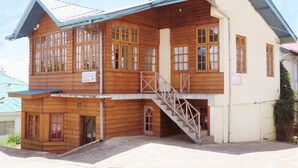 A two-story wooden building with a balcony, a staircase, and a sign indicating it is a Carnation Rest. - Carnation Rest (Nuwara Eliya)