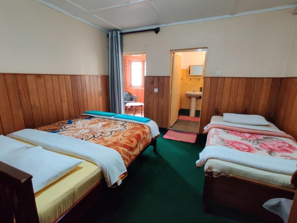 Ein Zimmer mit zwei Betten, einem kleinen Tisch und einer Tür zu einem Badezimmer.