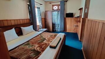 Habitación de hotel con cama, cortinas, televisión y ventana.