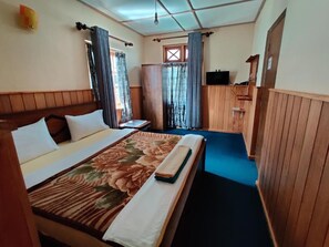 A hotel room with a bed, curtains, a television, and a window. - Carnation Rest (Nuwara Eliya)