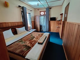 Quarto de hotel com cama, cortinas, televisão e janela.
