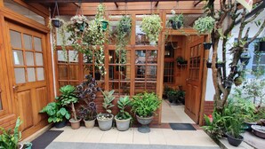 A wooden building with multiple windows and doors, surrounded by various potted plants and hanging plants. - Carnation Rest (Nuwara Eliya)