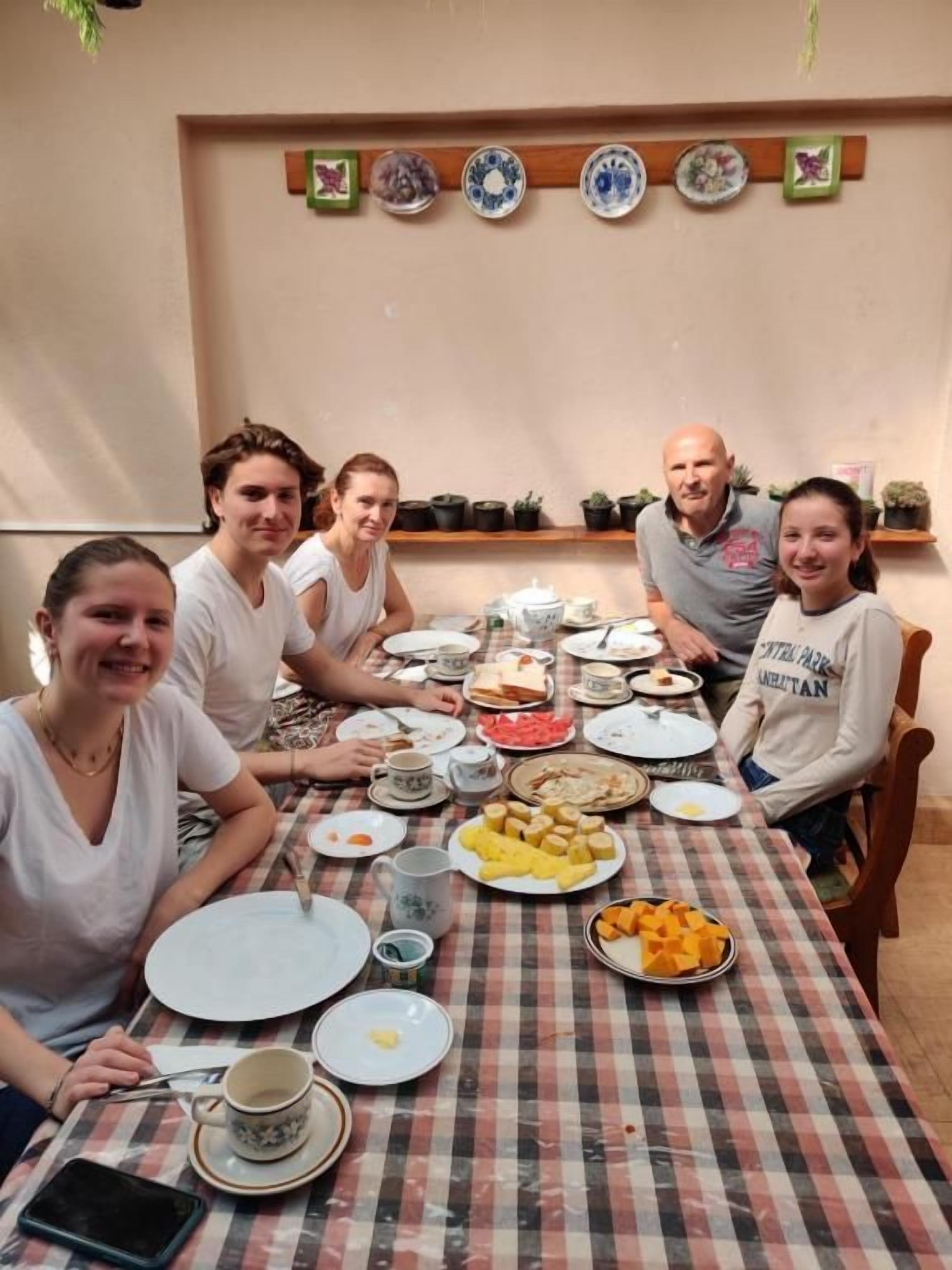 A group of people seated around a table with various dishes, plates, and cups.