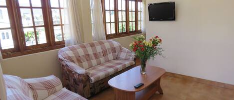 A living room with a checkered sofa, a wooden coffee table, and a TV mounted on the wall.