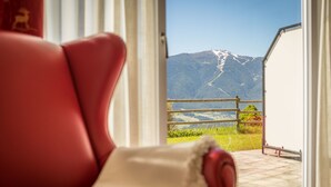 Una silla roja con un cojín blanco, una ventana con vistas a una montaña y un lago.