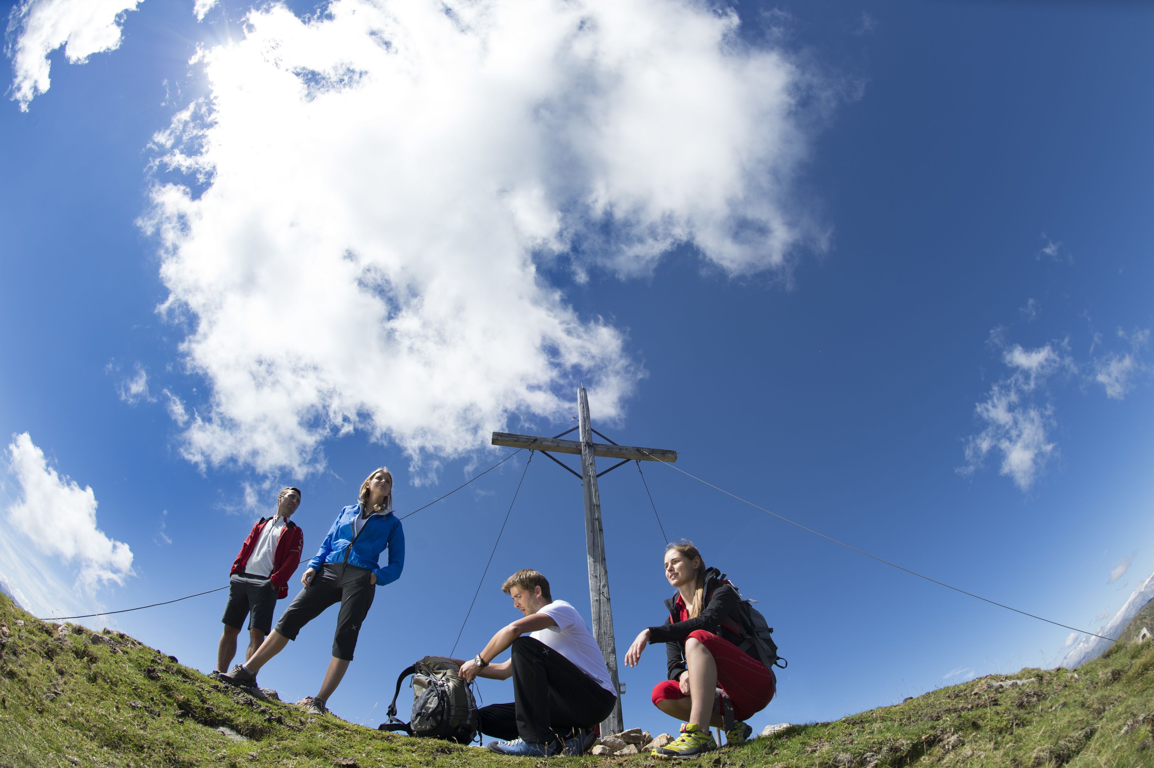 A group of people on a grassy hill with a clear sky.