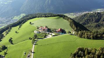 A rural landscape with a large green field, a few buildings, and a mountain in the background.