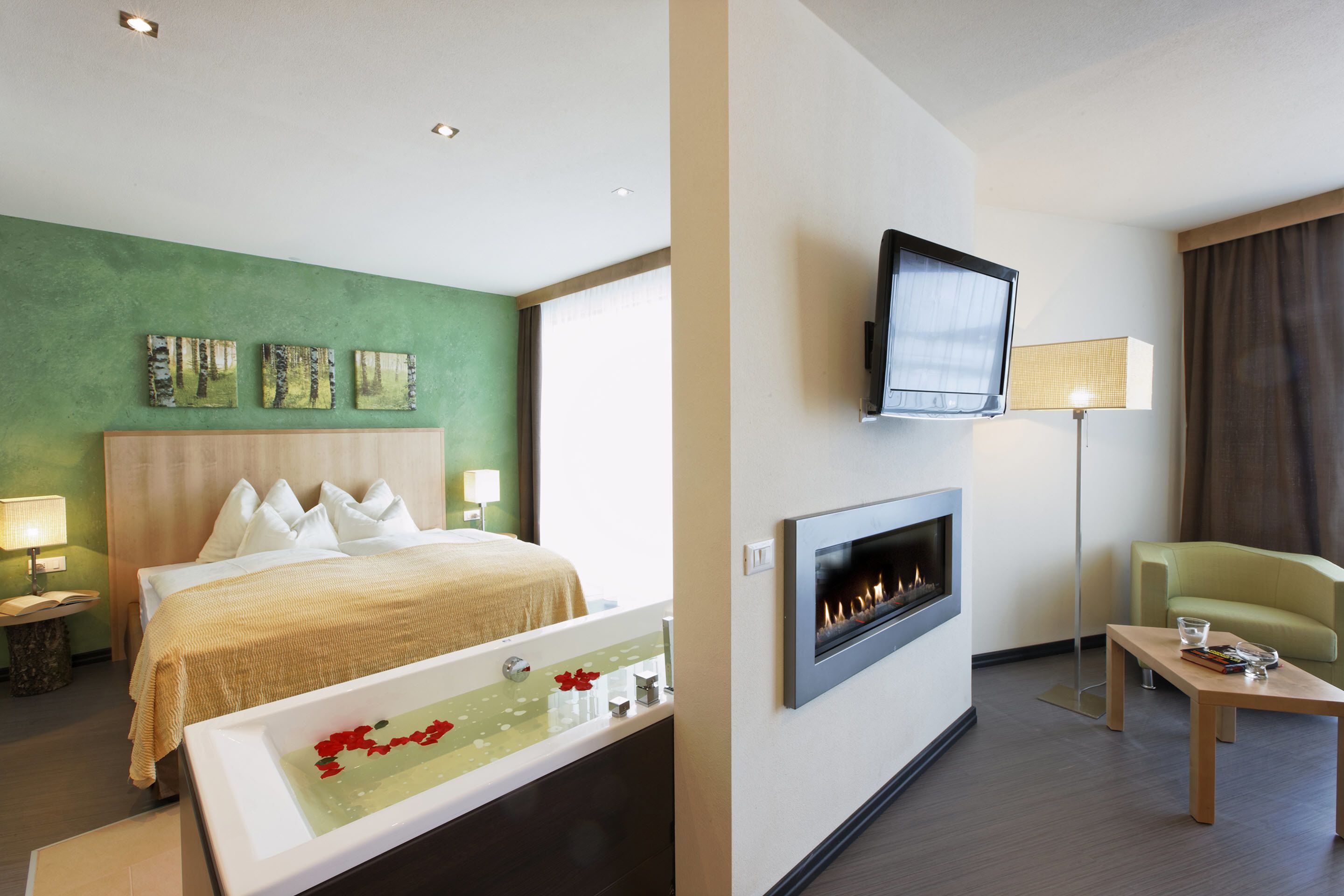Una habitación de hotel con cama, chimenea, televisión y zona de estar.