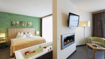 Una habitación de hotel con cama, chimenea, televisión y zona de estar.