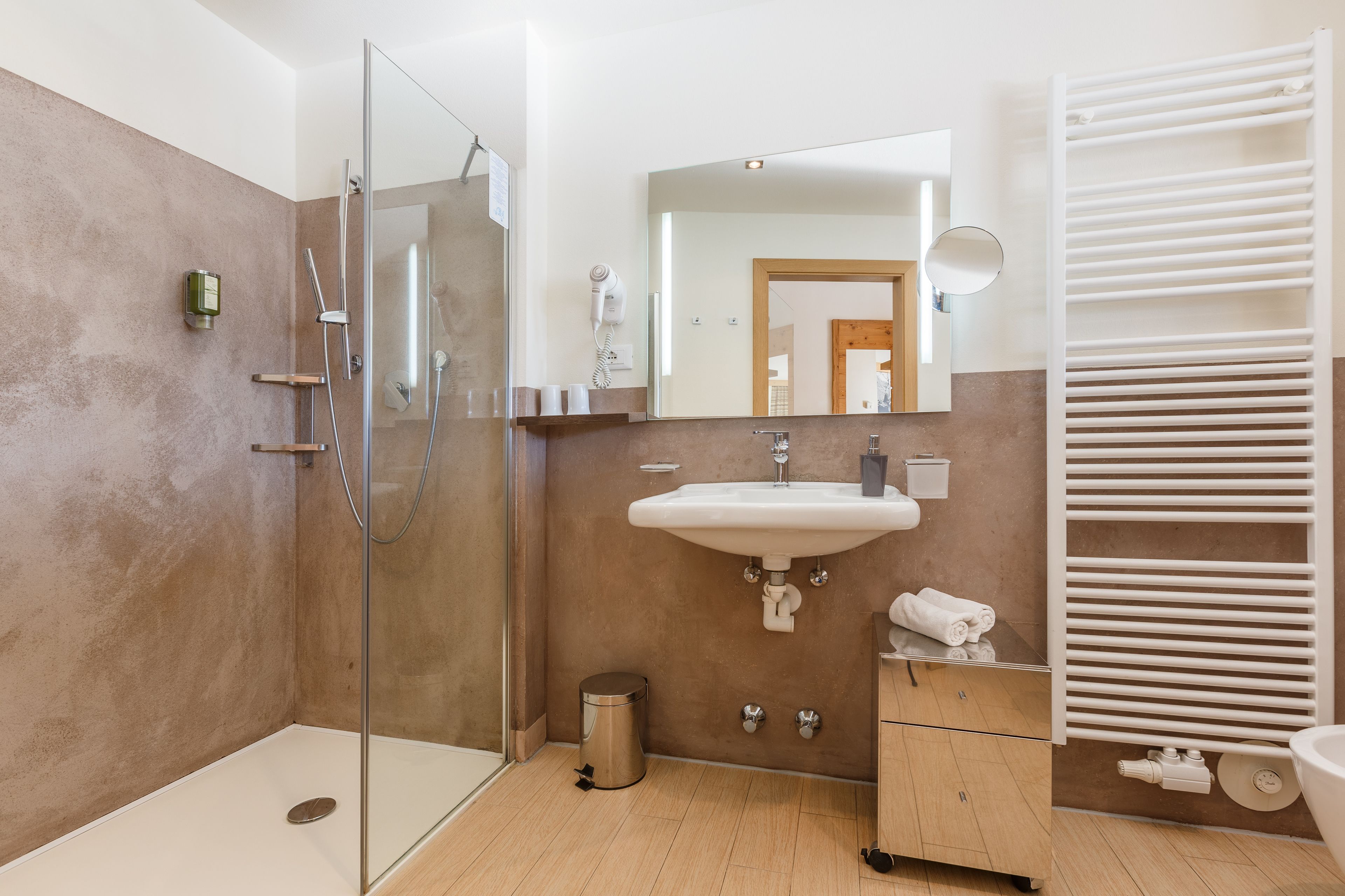 Ein modernes Badezimmer mit einer gläsernen Duschkabine, einem weißen Waschbecken und einem Handtuchhalter.