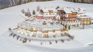 Un hotel cubierto de nieve con varios edificios, incluyendo un edificio rojo destacado y una gran estructura blanca con balcones.
