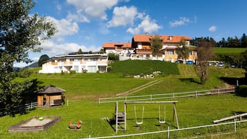 A hotel with multiple buildings, a grassy area with a swing set, and a fenced playground.