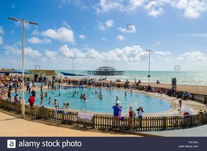 A public swimming pool surrounded by a wooden fence with people swimming and sunbathing. - Stay in the heart of.. Brighton (Brighton)