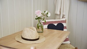 A wooden table with a straw hat and a vase with flowers.