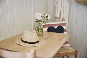 A wooden table with a straw hat and a vase with flowers. - Rønne Vandrerhjem - Hostel (Ronne)