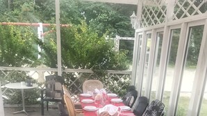A covered outdoor dining area with a red tablecloth, chairs, and a white lattice structure.