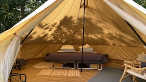 A tent with a bed, a chair, and a yoga mat.