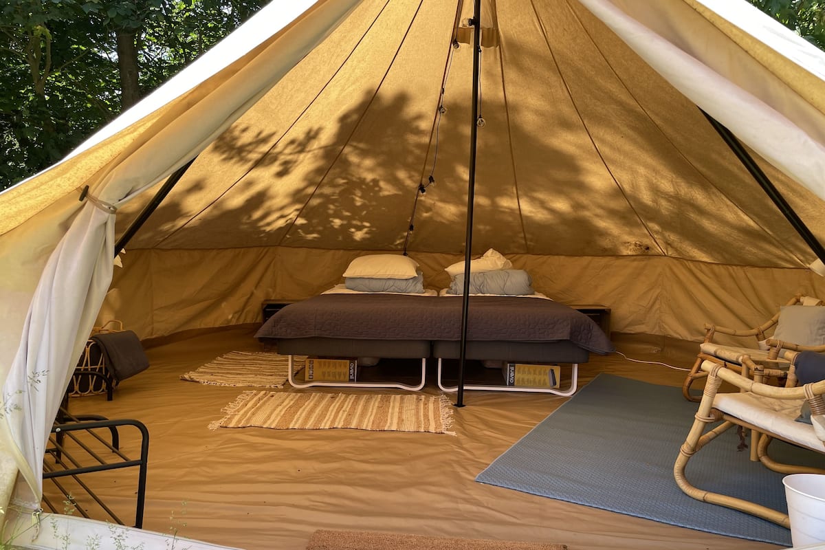 A tent with a bed, a chair, and a yoga mat.