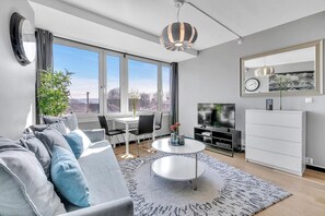 Un salon moderne comprenant un canapé, un téléviseur, une table à manger, des chaises et une grande fenêtre donnant sur un beau paysage.