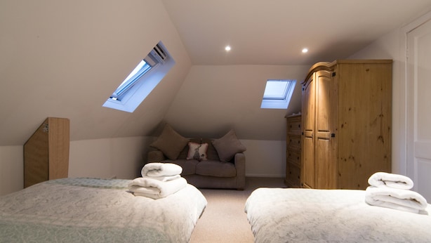 A bedroom with two beds, a sofa, a wardrobe, and skylights. - Blair Drummond Holiday Home (Doune)
