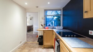 A modern kitchen with a built-in oven, a window with blinds, and a view of the outdoors. - Blair Drummond Holiday Home (Doune)