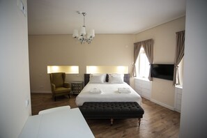 A hotel room with a bed, bedside lamps, a chair, a TV, and a wooden floor. - Sui7es Guest House Cascais (Cascais)