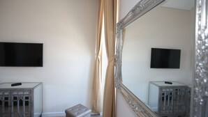 A room with a large mirror, two TV screens, and a cabinet with a remote control. - Sui7es Guest House Cascais (Cascais)
