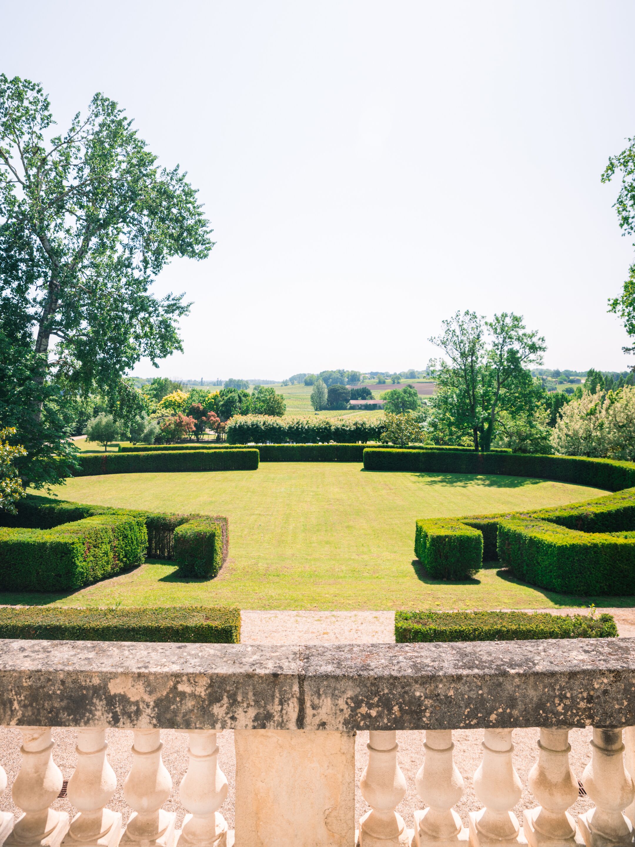 A formal garden with neatly trimmed hedges and a clear view of the landscape beyond.