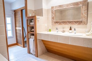 Un baño con dos lavamanos, un espejo grande y un perchero para toallas.