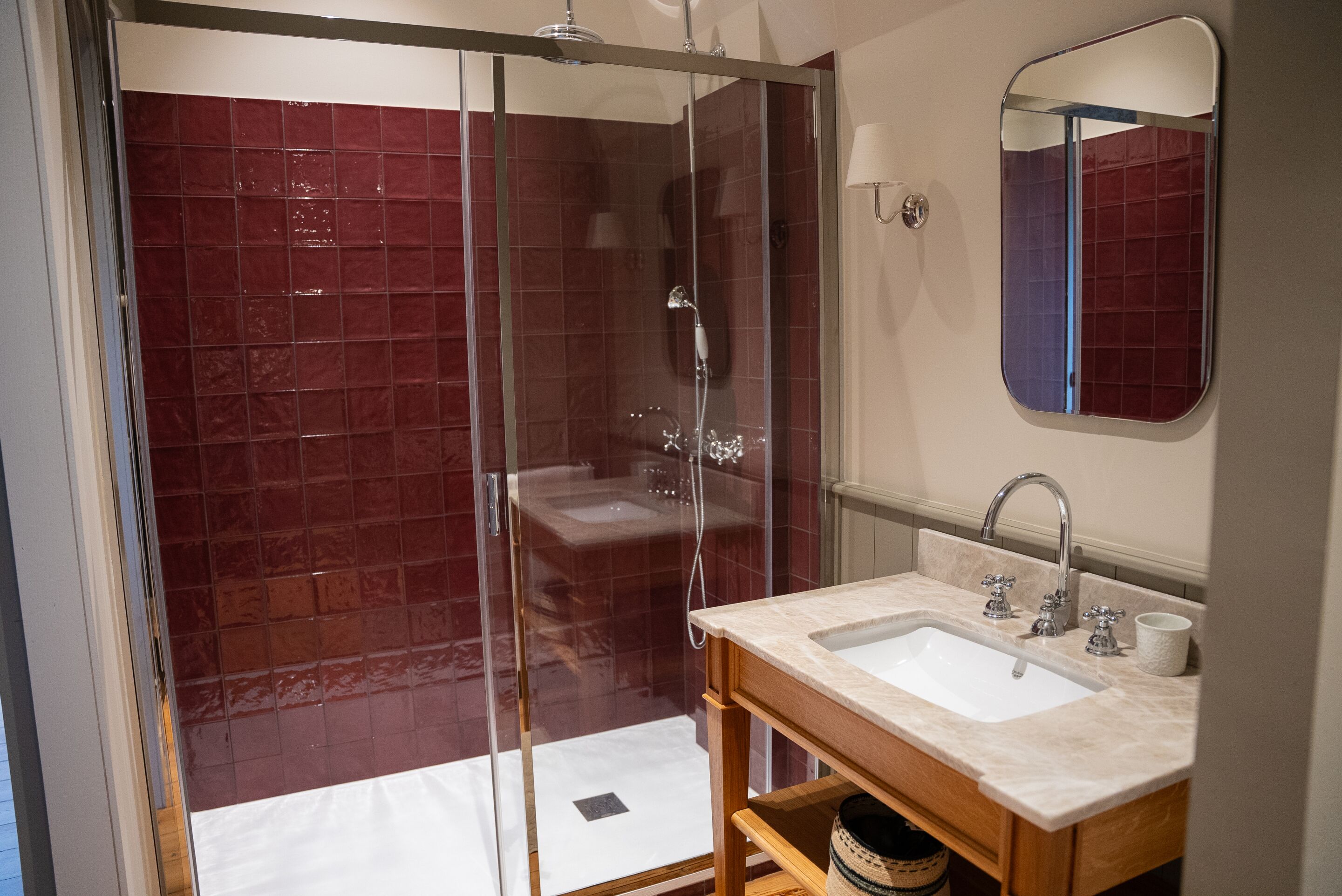 A bathroom with a glass-enclosed shower, a sink with a mirror, and a wooden vanity.