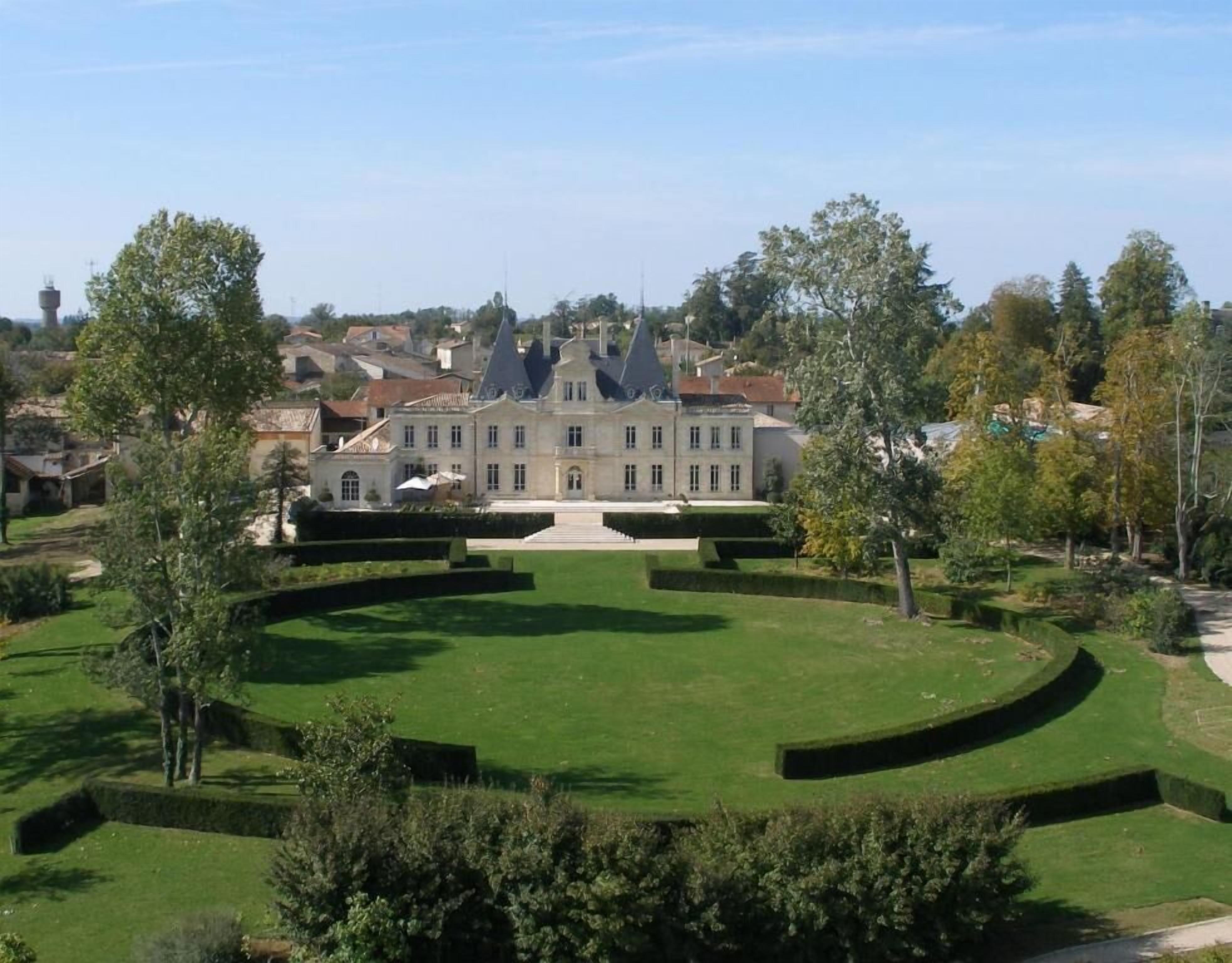 A large, historic building with a symmetrical garden and a central fountain.