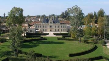 Un grand bâtiment historique doté d’un jardin symétrique et d’une fontaine centrale.