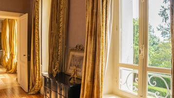 A room with a wooden floor, a black dresser with drawers, a framed picture, and a window with a white balustrade.