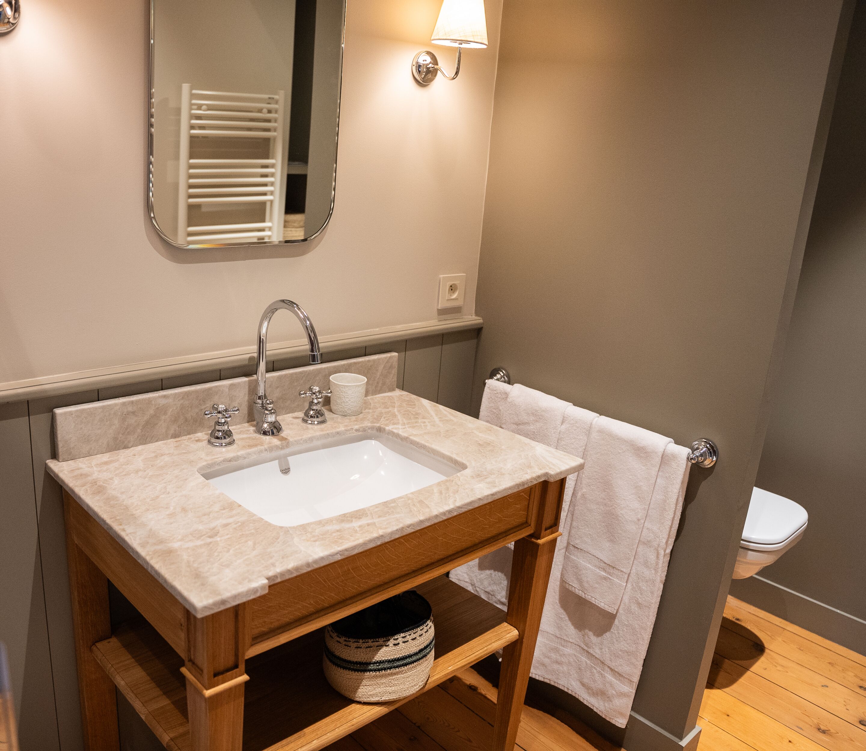 Une salle de bain équipée d’un lavabo, d’un miroir, d’un porte-serviettes et de toilettes.