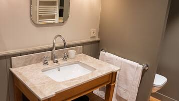 Une salle de bain équipée d’un lavabo, d’un miroir, d’un porte-serviettes et de toilettes.