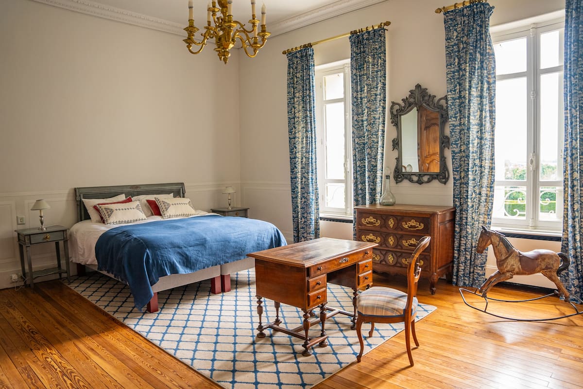 A bedroom with a bed, a wooden desk, a chair, a dresser, and a rocking horse.