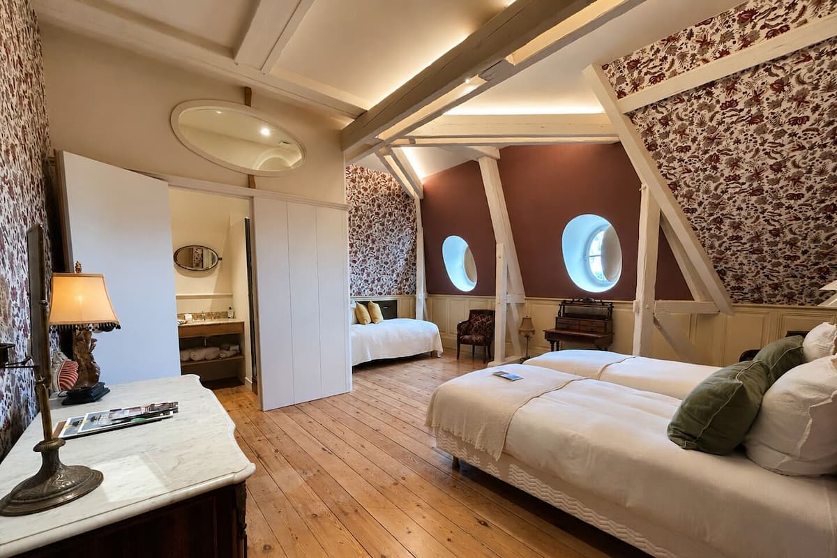 A bedroom with two beds, a desk, a chair, and a piano.
