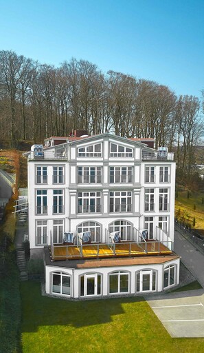 A multi-story building with a flat roof and a balcony with chairs. - Hotel Seeschloss Sellin (Sellin)