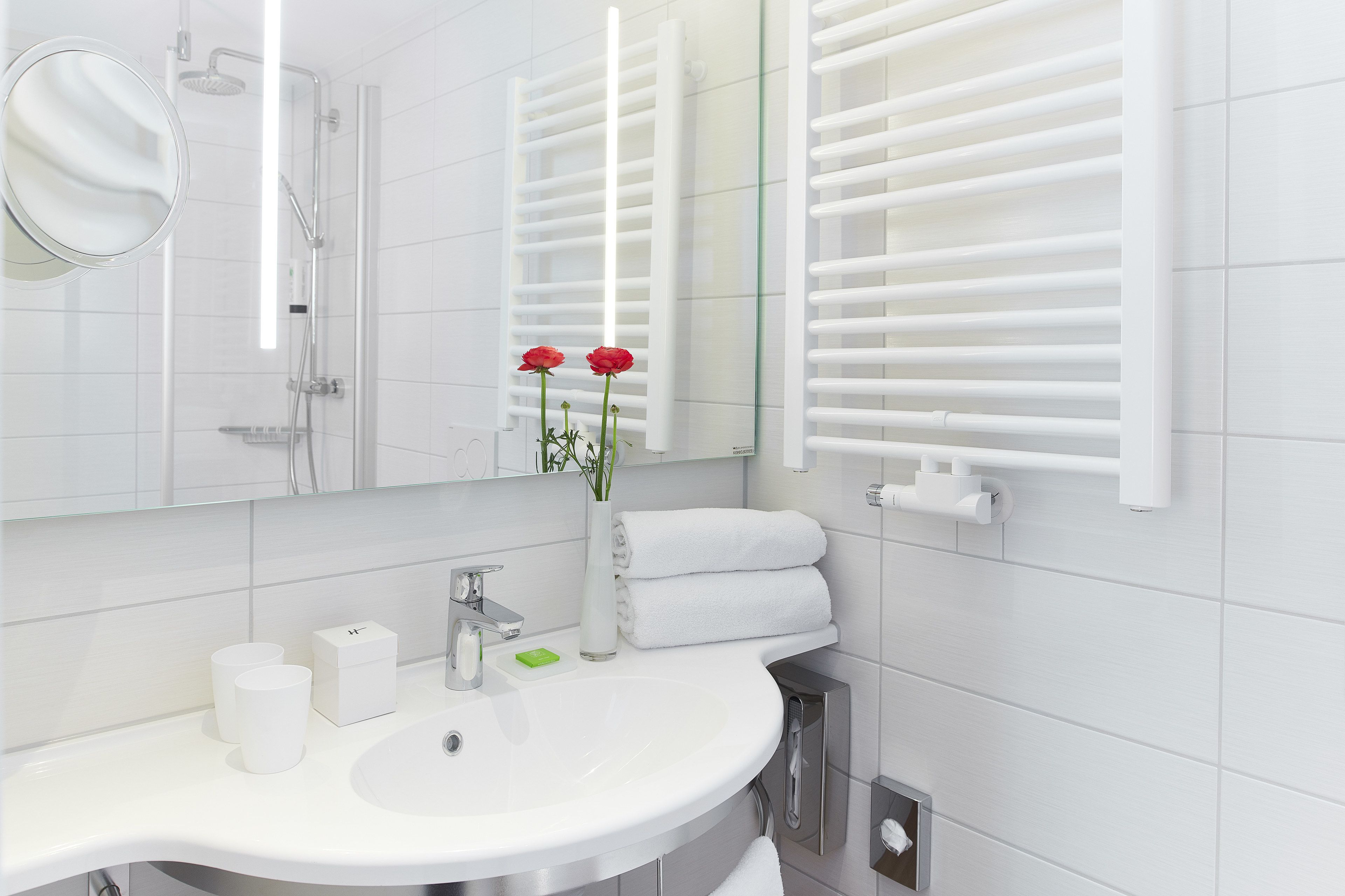 A modern bathroom with a white sink, mirror, and towel rack.
