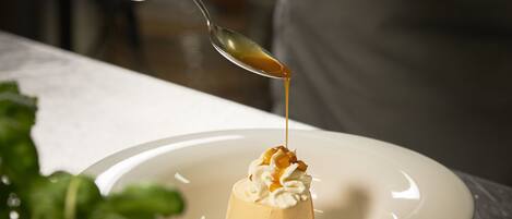 A dessert on a plate with a spoon pouring sauce over it.