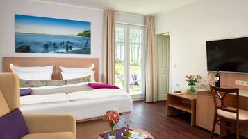 Una habitación de hotel con una cama, un escritorio, un televisor y un cuadro de una playa.