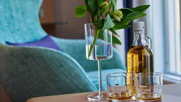 A table with a bottle of single malt whiskey, two shot glasses, and a glass with a flower arrangement.