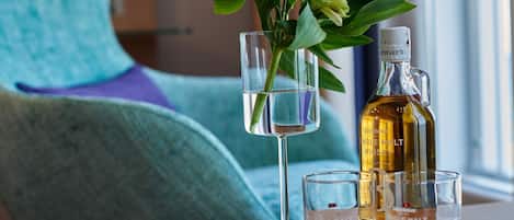 A table with a bottle of single malt whiskey, two shot glasses, and a glass with a flower arrangement.